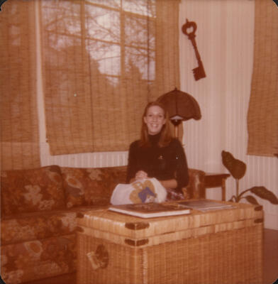 unidentified epsilon tau chapter member on patterned couch photograph, c. 1977 (image)