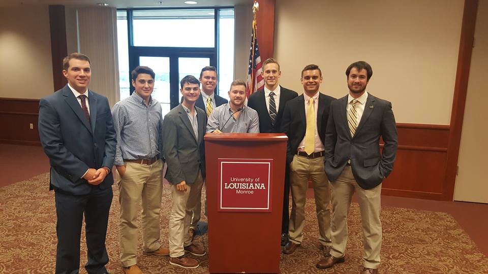 Eight Eta Omicron Chapter Members Stand Around A Lectern Photograph
