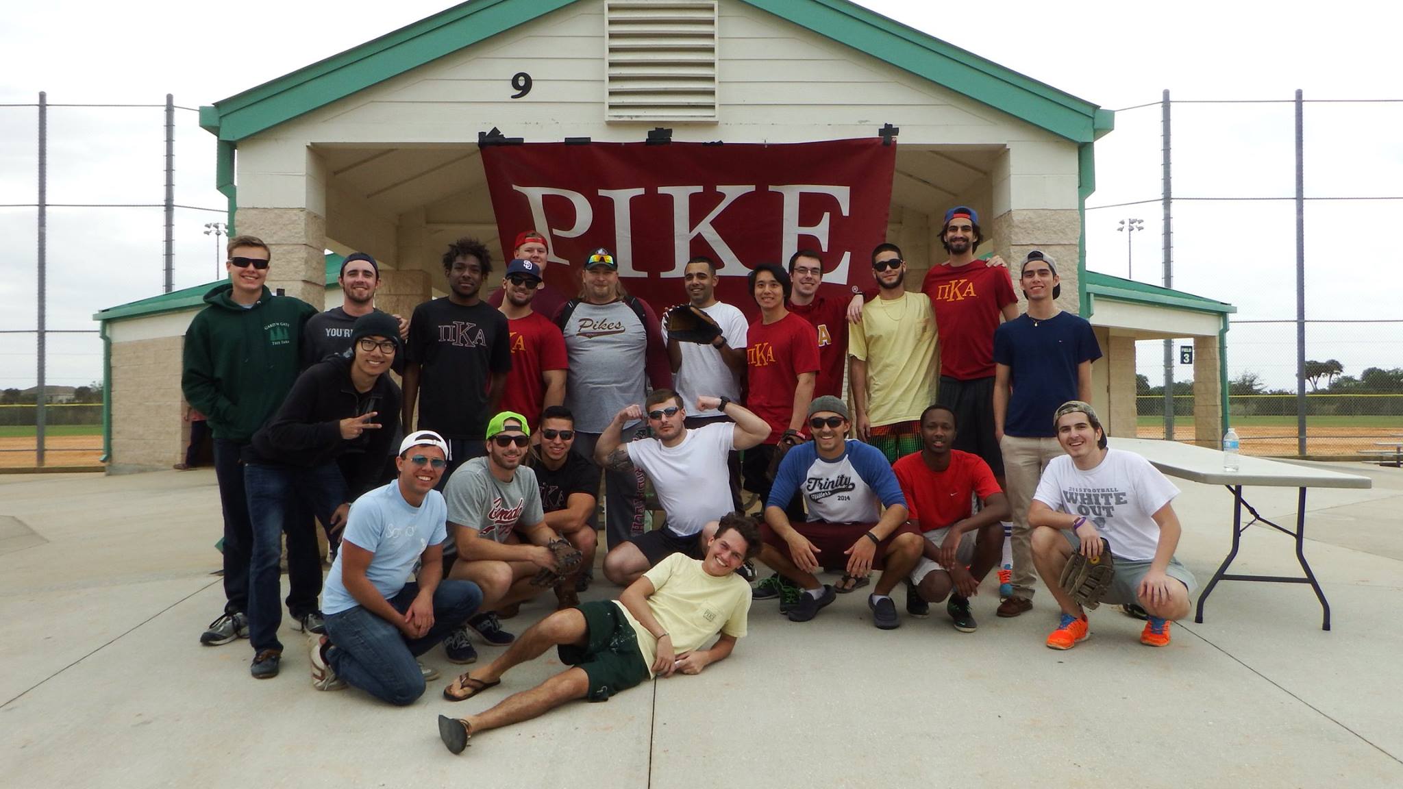 Zeta Sigma Chapter Members Stand with a PIKE Flag Outside Of A Baseball Diamond Photograph