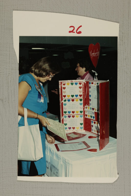 Unidentified Phi Mu Looking at Convention Exhibit Photograph, July 6-10, 1986 (Image)