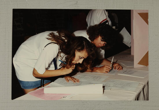 Two Phi Mus Filling Out Forms at Convention Photograph, July 1-5, 1988 (image)