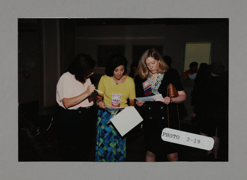 Three Phi Mus Looking Over Convention Materials Photograph, July 3-5, 1998 (Image)
