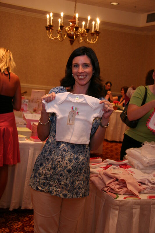 Unidentified Phi Mu Holding Baby Clothes in Convention Marketplace Photograph, July 2006 (Image)