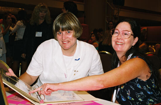 Two Phi Mus Looking Through a Photograph Album at Convention Photograph, July 4-8, 2002 (image)