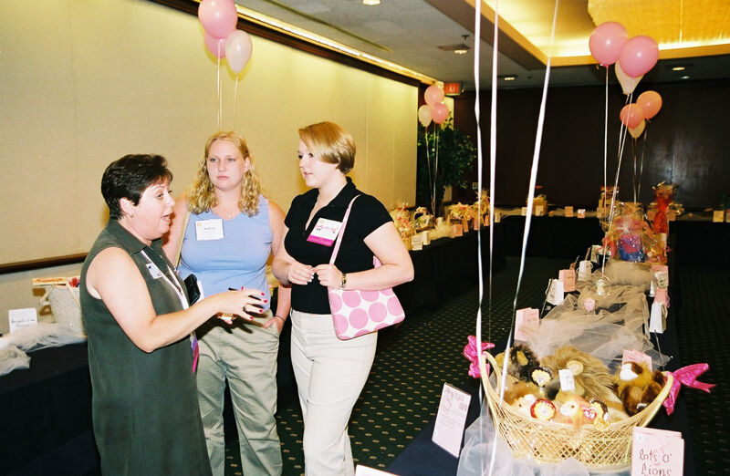 McNamara, Alford, and Unidentified in Convention Gift Basket Display Photograph 1, July 4-8, 2002 (Image)