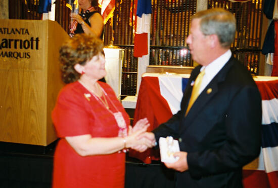 Mary Jane Johnson Presenting Gift to Johnny Isakson at Convention Welcome Dinner Photograph 1, July 4, 2002 (image)