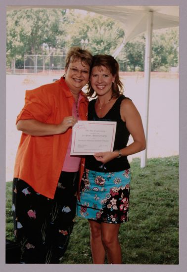 Kathy Williams and Northeast Arkansas Alumna With Certificate at Convention Outdoor Luncheon Photograph 1, July 10, 2004 (image)