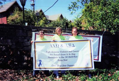 Epsilon Rho (University of Delaware) members with domestic violence 5k walk/run event banner, ca. 2000, photograph