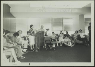 Miriam Herman and Max Baer Speaking at Podium Photograph, July 1978