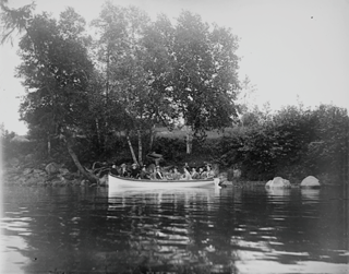 Twelve young women rowing close to the Indian Point Shore, Union River, Ellsworth ME.