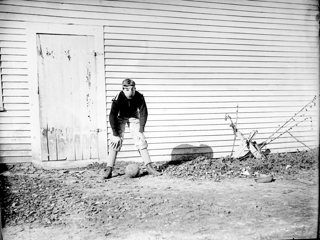 Ted Higgins by Gil's barn, standing above football wearing nose protector.