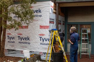 Students fixing siding on the Arts and Sciences Building