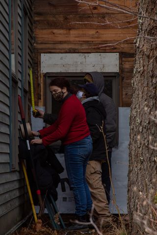Students fixing siding on the Arts and Sciences Building