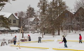 Students shoveling snow off the campus ice rink