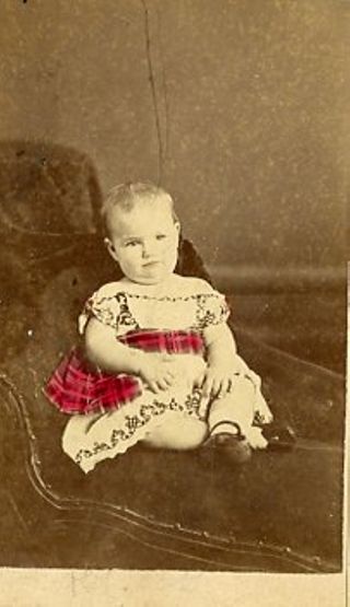 Hand colored print of baby in white dress with black trim