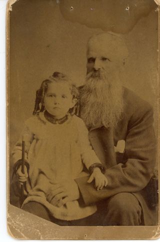 Portrait of young girl sitting on knee of elderly man