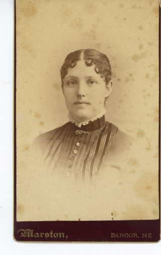 Woman with dark hair wearing dark dress with stripped details