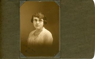 Woman in white dress and round glasses