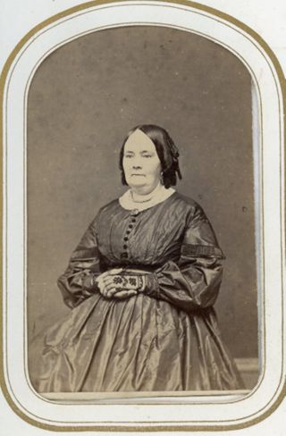 Woman seated in dark dress black lace gloves