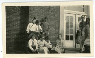Seven children next to brick building