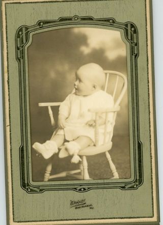 Baby wearing white dress seated in chair