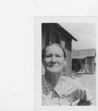 B&W photograph of a woman's face with 2 buildings in the background.
