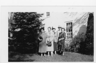 B&W photo of 2 men and 4 women standing in front of a white wood.sided house.