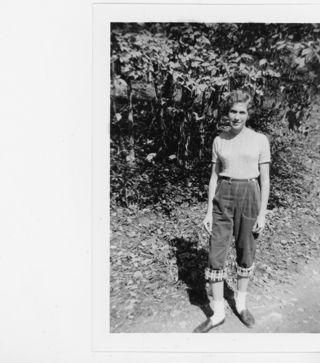 B&W photograph of a young woman standing outside.