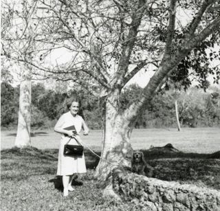 Louise Gilbert with a dog standing under a tree