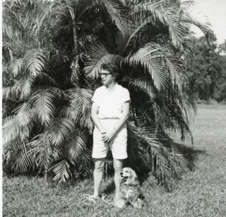 LaRue Spiker and her dog standing in front of a Sago Palm