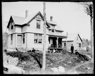 Family posing on lawn and porch at Merrill cottage, Green Lake