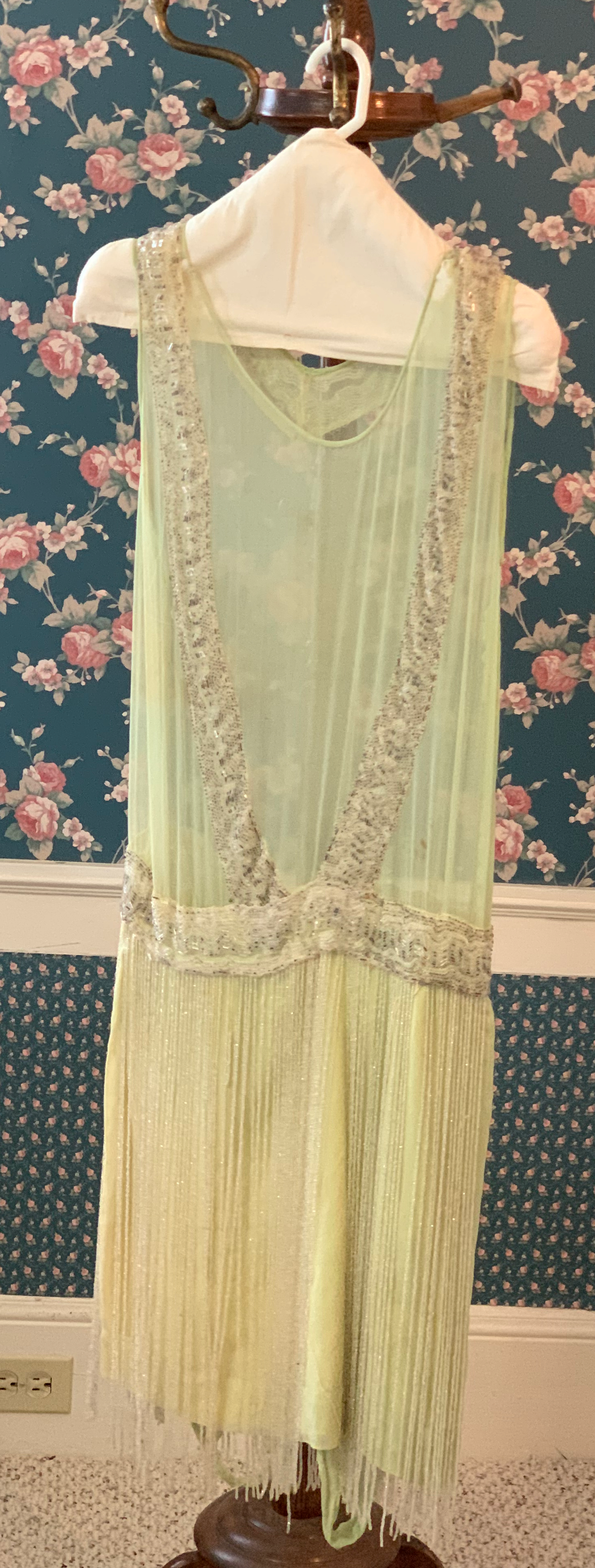 Sleeveless yellow dress with dropped waist, front trim, and fringe at hem