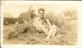 young Paul Hinton sitting in a field with a cat